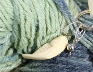 Ivory-like fish stitch marker with silver droplet and hand-dyed American wool yarn.